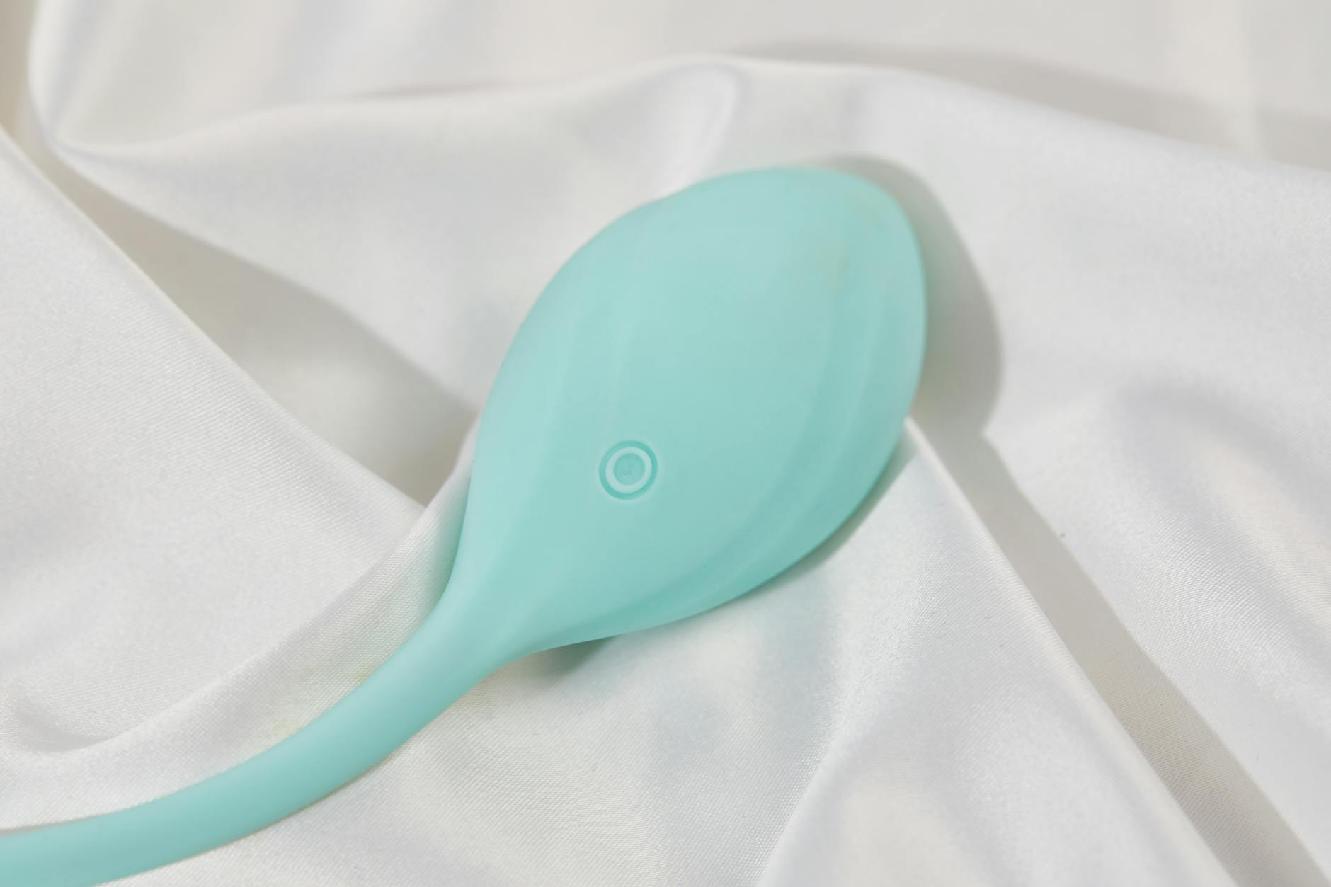 Una mano sostiene un vibrador azul sobre un recipiente de vidrio decorativo