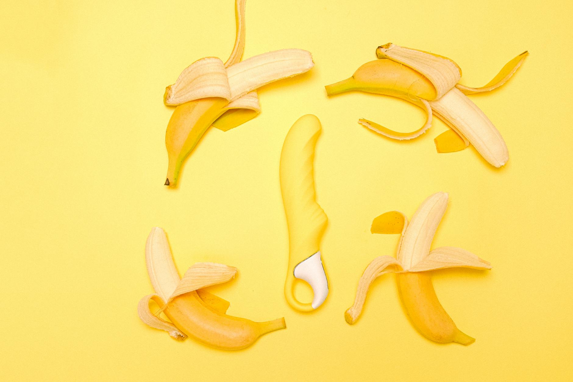 Yellow silicone vibrator with fresh lemons on a yellow background