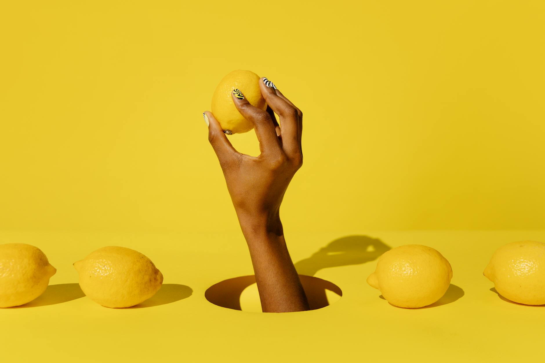 A hand holding a lemon against a vivid yellow background, symbolizing fresh self-discovery and solo pleasure