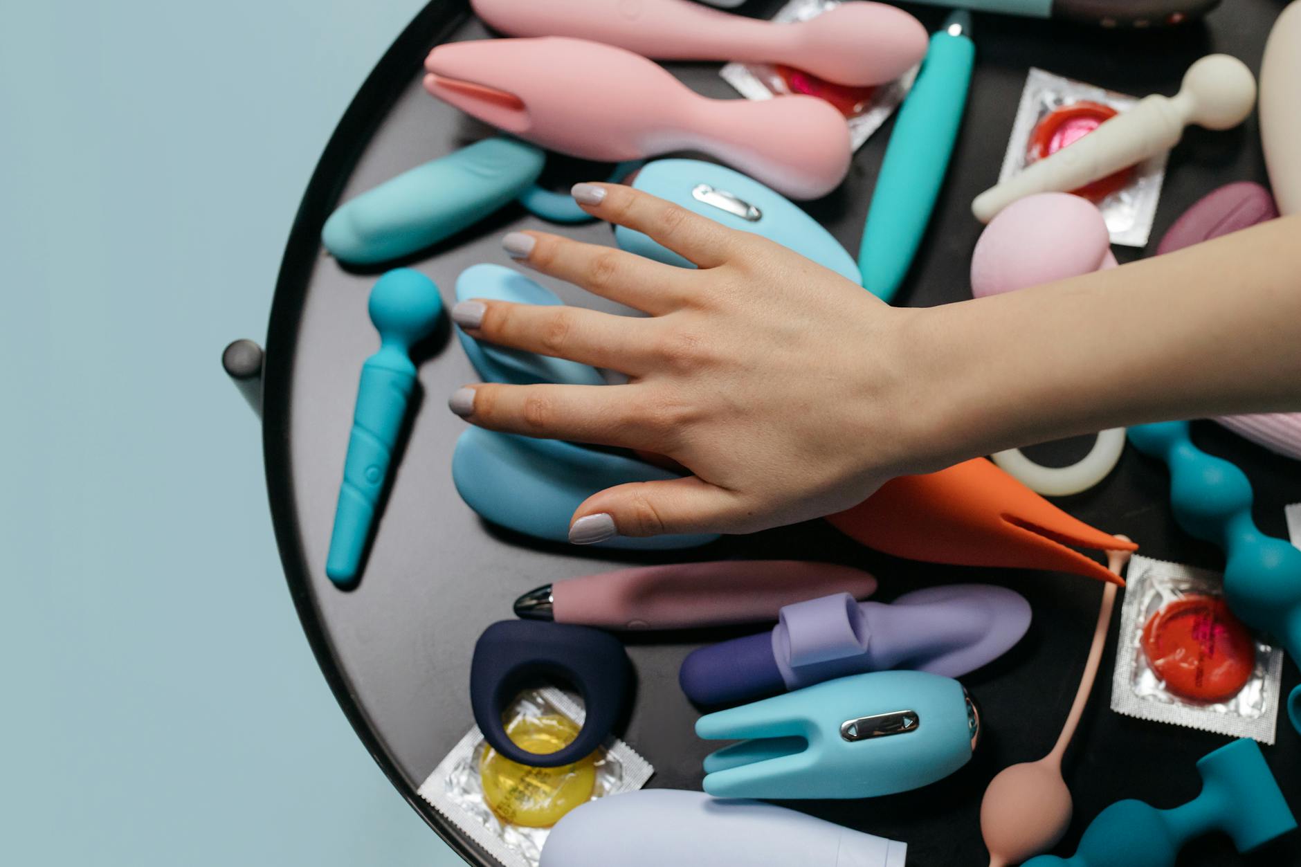 Intimate close-up of hands holding a sleek blue vibrator against a purple background.
