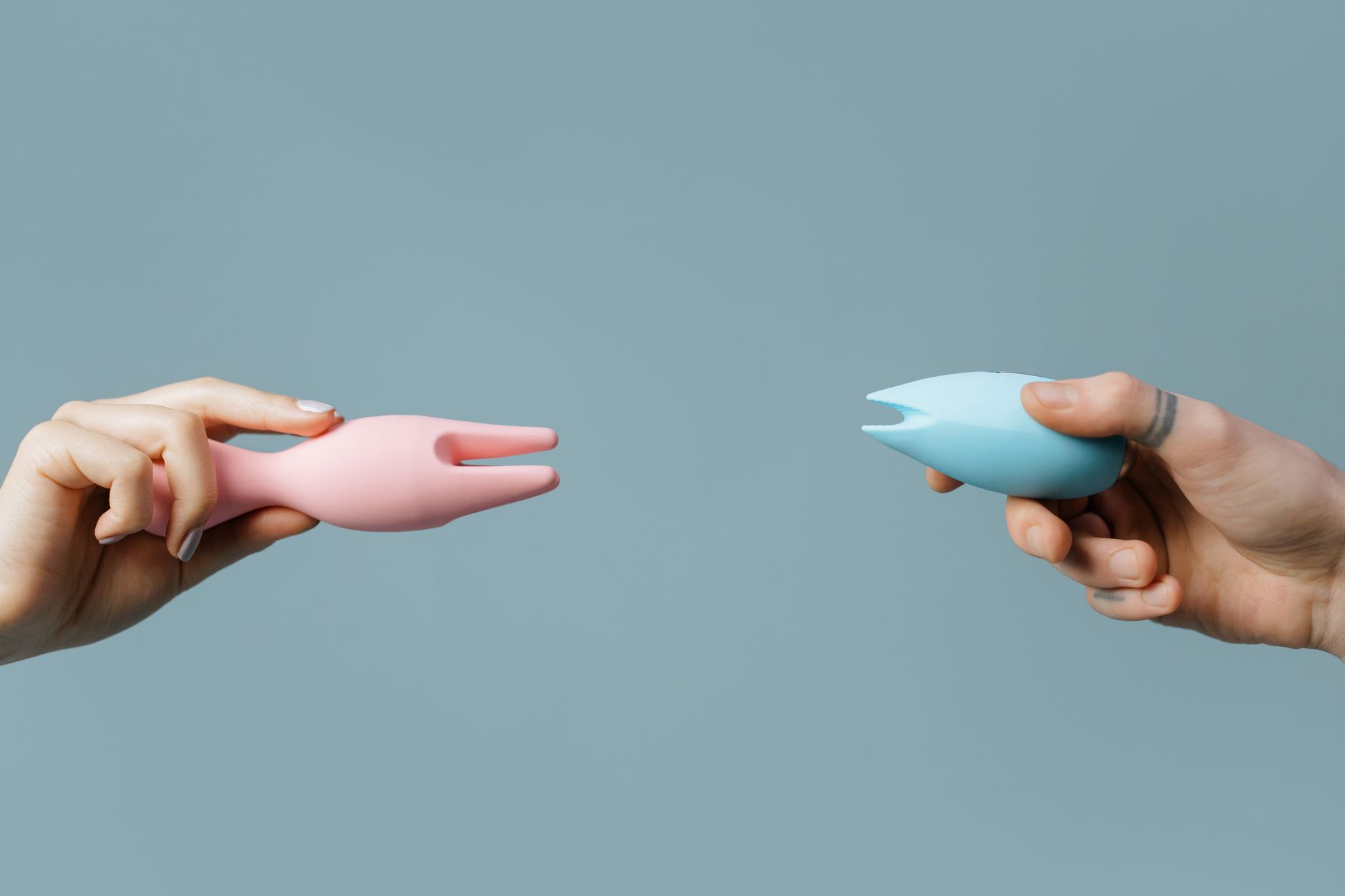 Close-up of a hand holding an orange clitoral vibrator against a purple backdrop, symbolizing reconnection with pleasure.