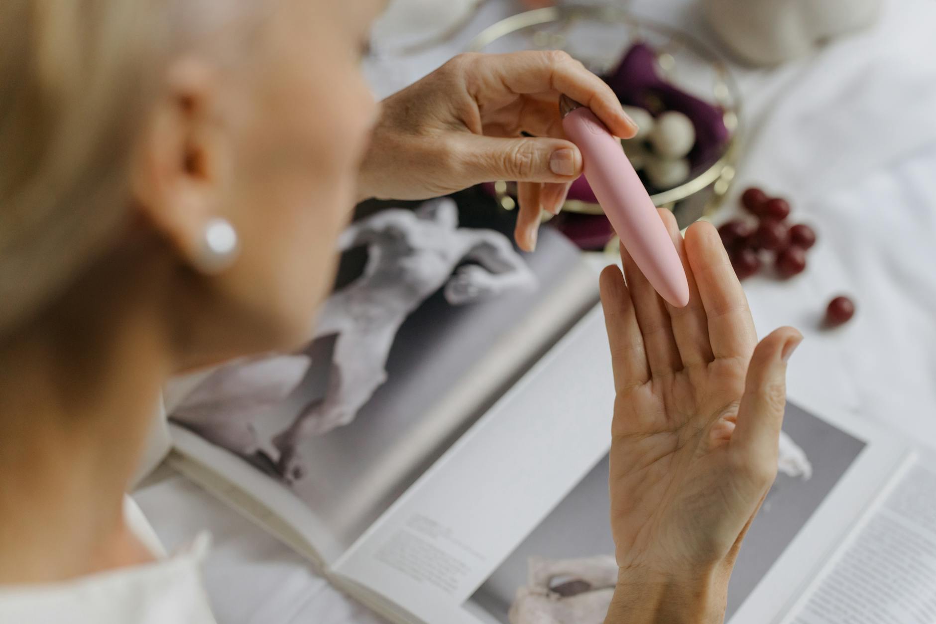 A woman holding a vibrator surrounded by self-care items