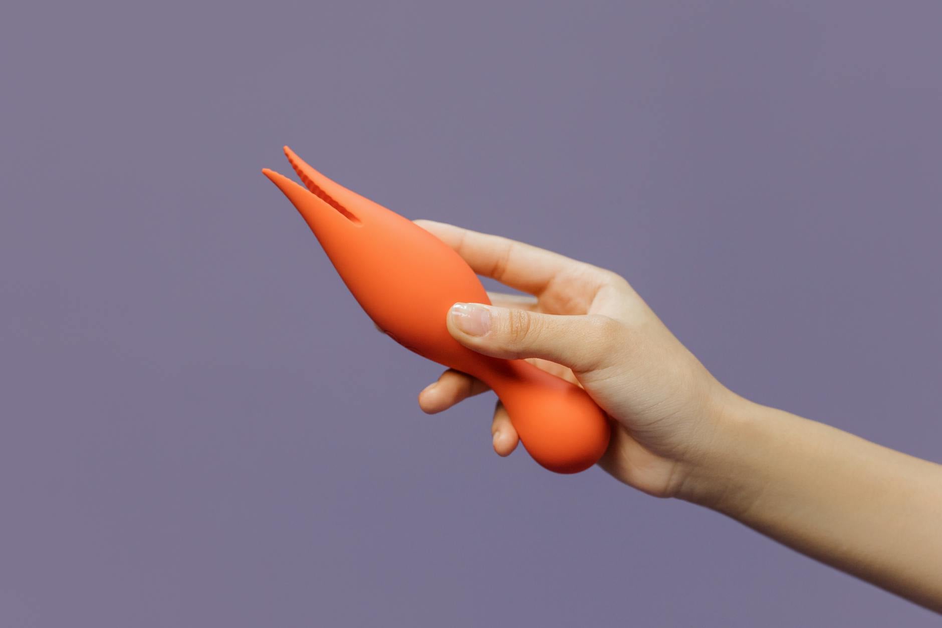 Close-up of a hand holding a Lemon vibrator against a minimalistic purple backdrop showcasing modern pleasure design
