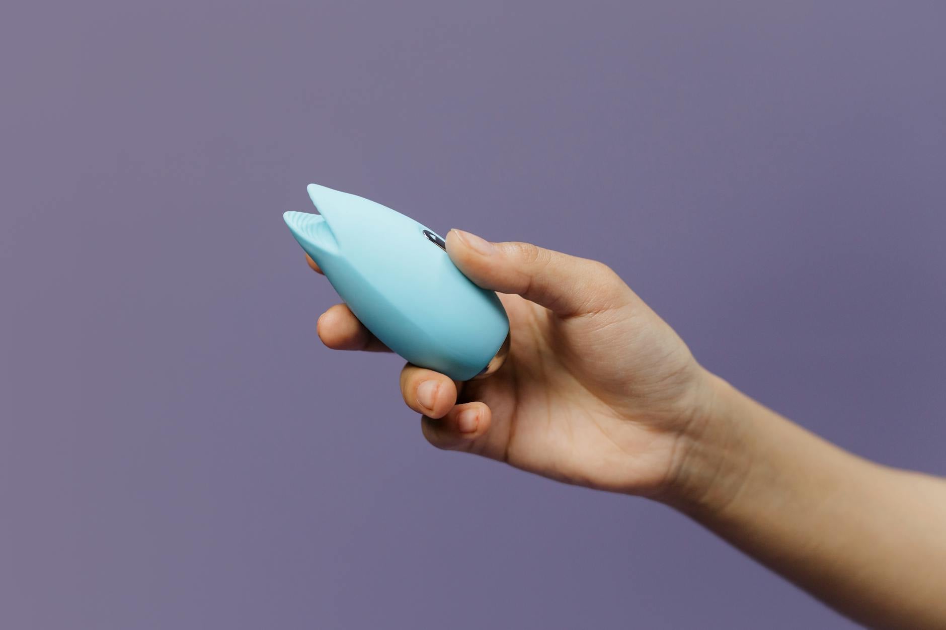 A blue silicone vibrator held against a purple background, symbolizing self-care and reconnection