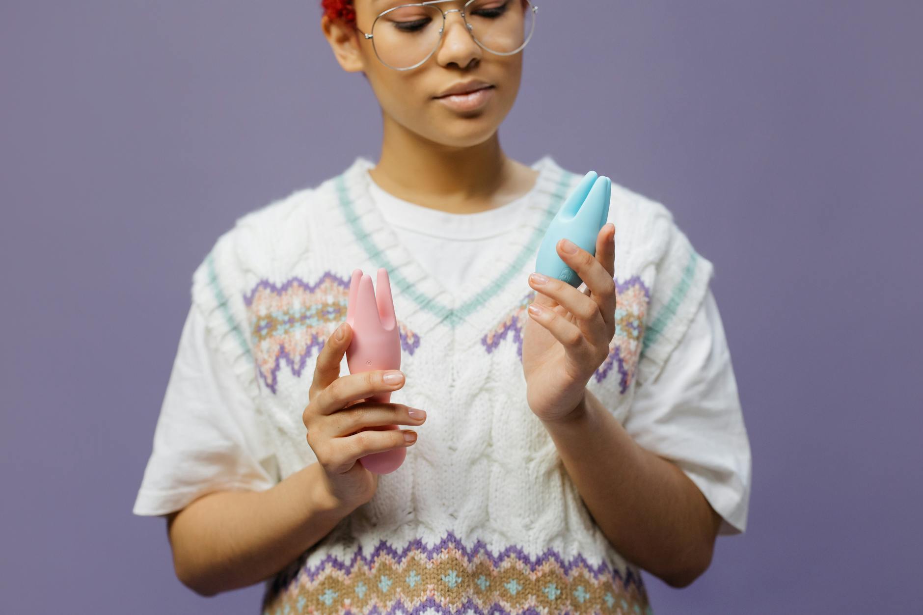 Woman holding a blue clitoral vibrator with focused expression