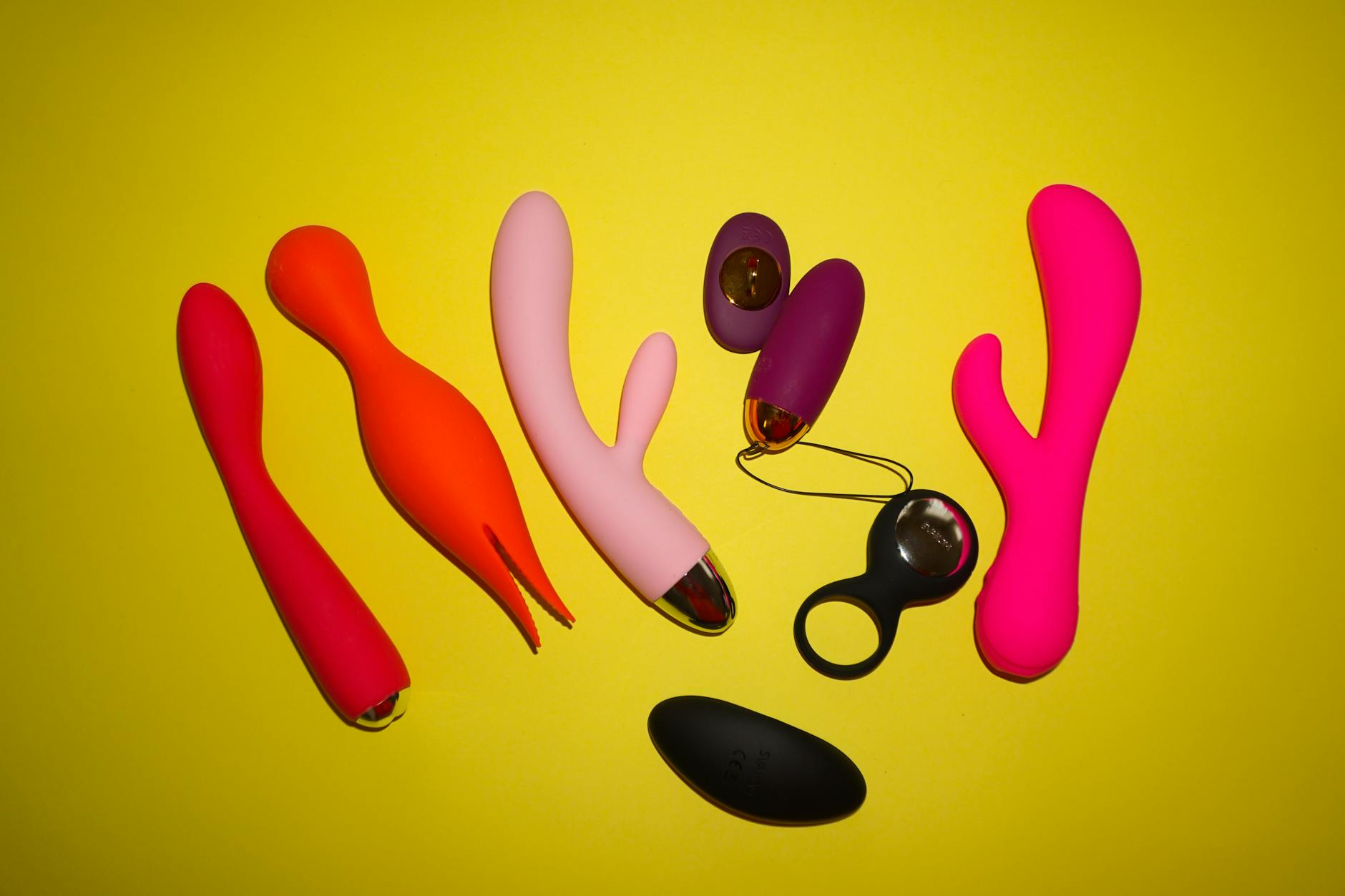 Colorful clitoral vibrators and sex toys on a bright yellow background